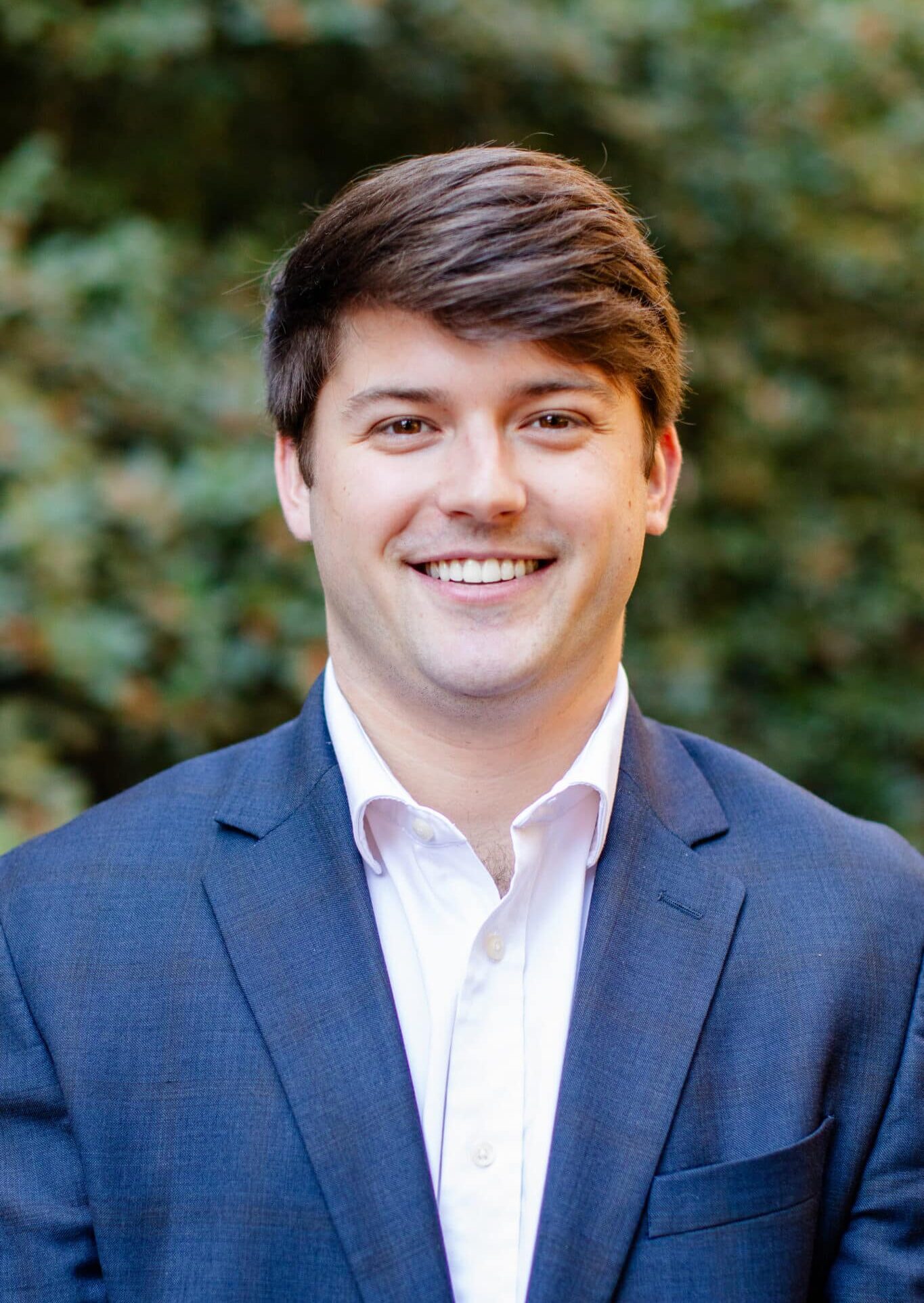 a man wearing a suit and tie smiling at the camera