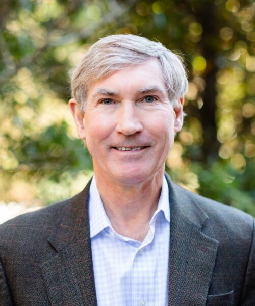 Tom Carruthers Wearing A Suit And Tie Smiling At The Camera