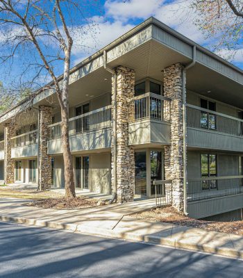 Exterior View Of A Multi-family Residential Building With Stone Accents, Surrounded By Parked Cars, Highlighting Available Residential Properties