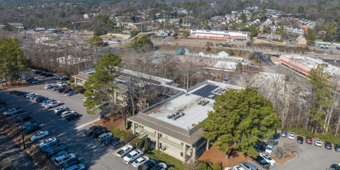 Exterior View Of A Commercial Building Featuring A Few Signage, Surrounded By Parked Vehicles And Trees, Representing Available Commercial Real Estate Opportunities