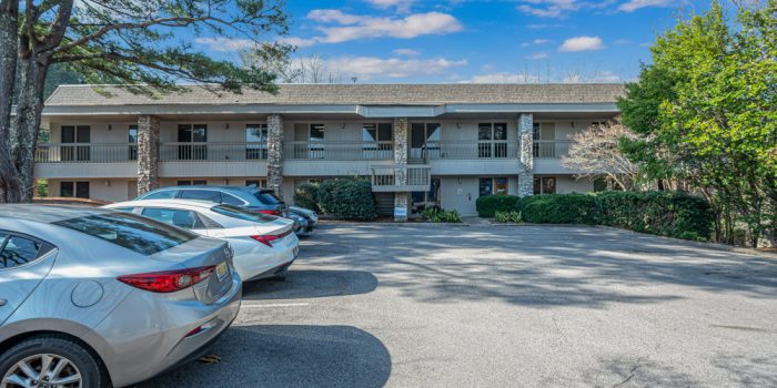 Exterior View Of A Multi-family Residential Building With Stone Accents, Surrounded By Parked Cars, Highlighting Available Residential Properties