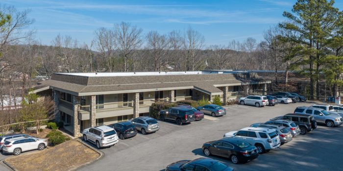 Exterior View Of A Residential Building Surrounded By Parked Vehicles And Trees, Representing Available Residential Real Estate Opportunities