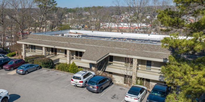 Exterior View Of A Commercial Building Featuring A Few Signage, Surrounded By Parked Vehicles And Trees, Representing Available Commercial Real Estate Opportunities