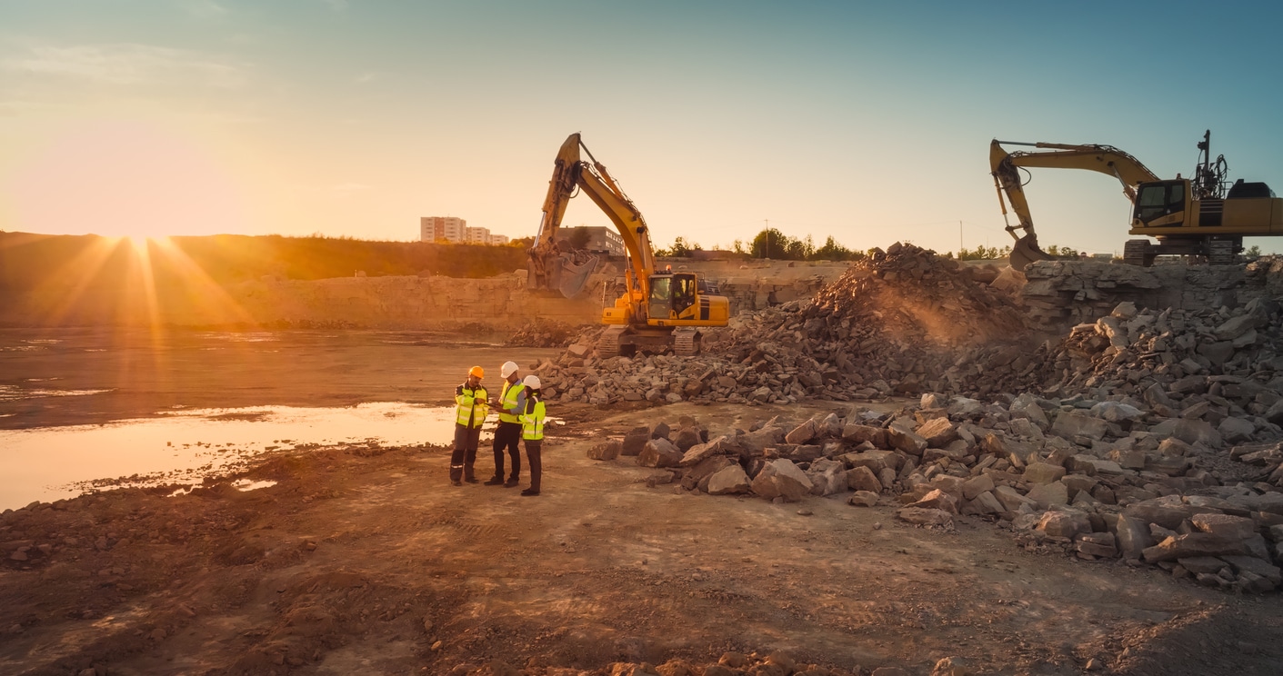 An aerial shot of a commercial construction site with excavators and real estate developers discussing the project.
